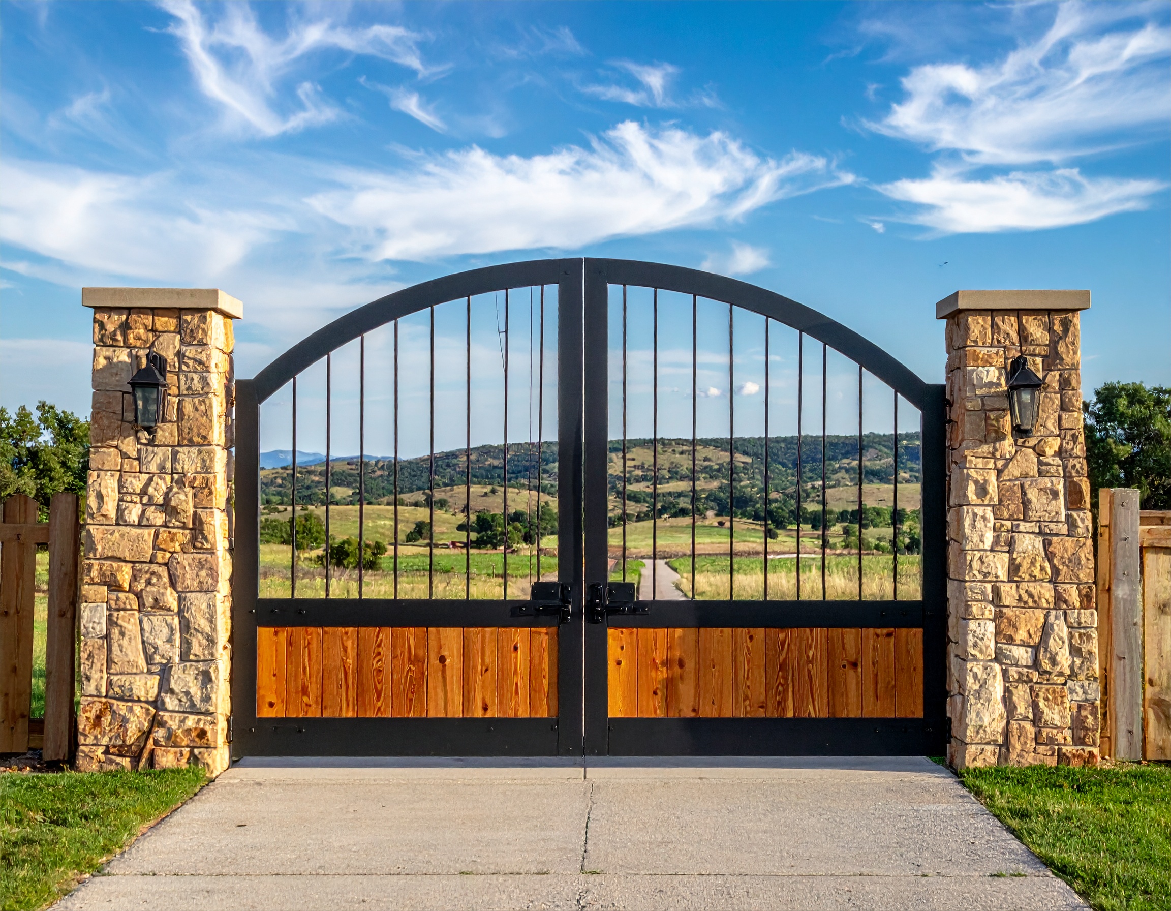 Arched Ranch Gate with Wood and Iron Mix_A custom ranch entrance with tall stone colu 399958 - San Antonio Deck and Fence Works Black metal gate with stone pillars.-deck builder-San Antonio, Texas