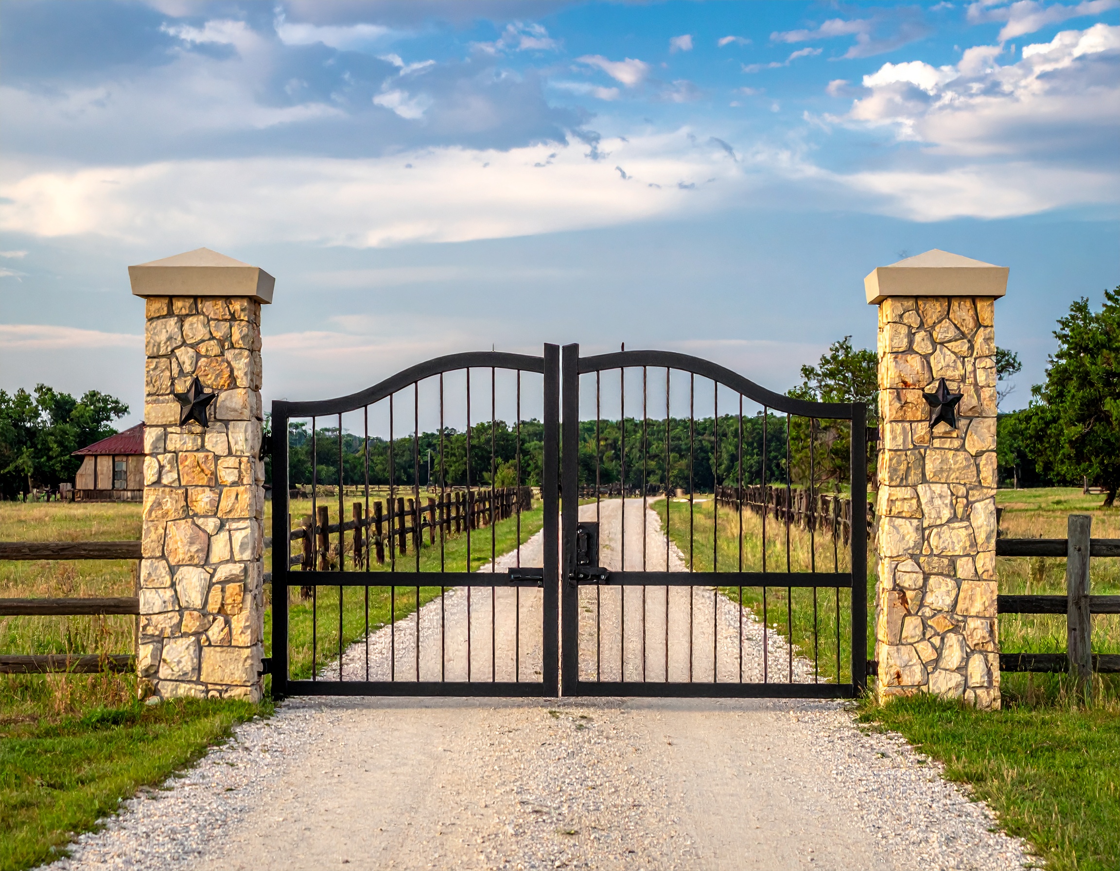 Classic Texas Ranch Gate with Curved Iron Design_A ranch driveway gate with limestone 399958 - San Antonio Deck and Fence Works Black metal gate with stone pillars-deck builder-San Antonio, Texas