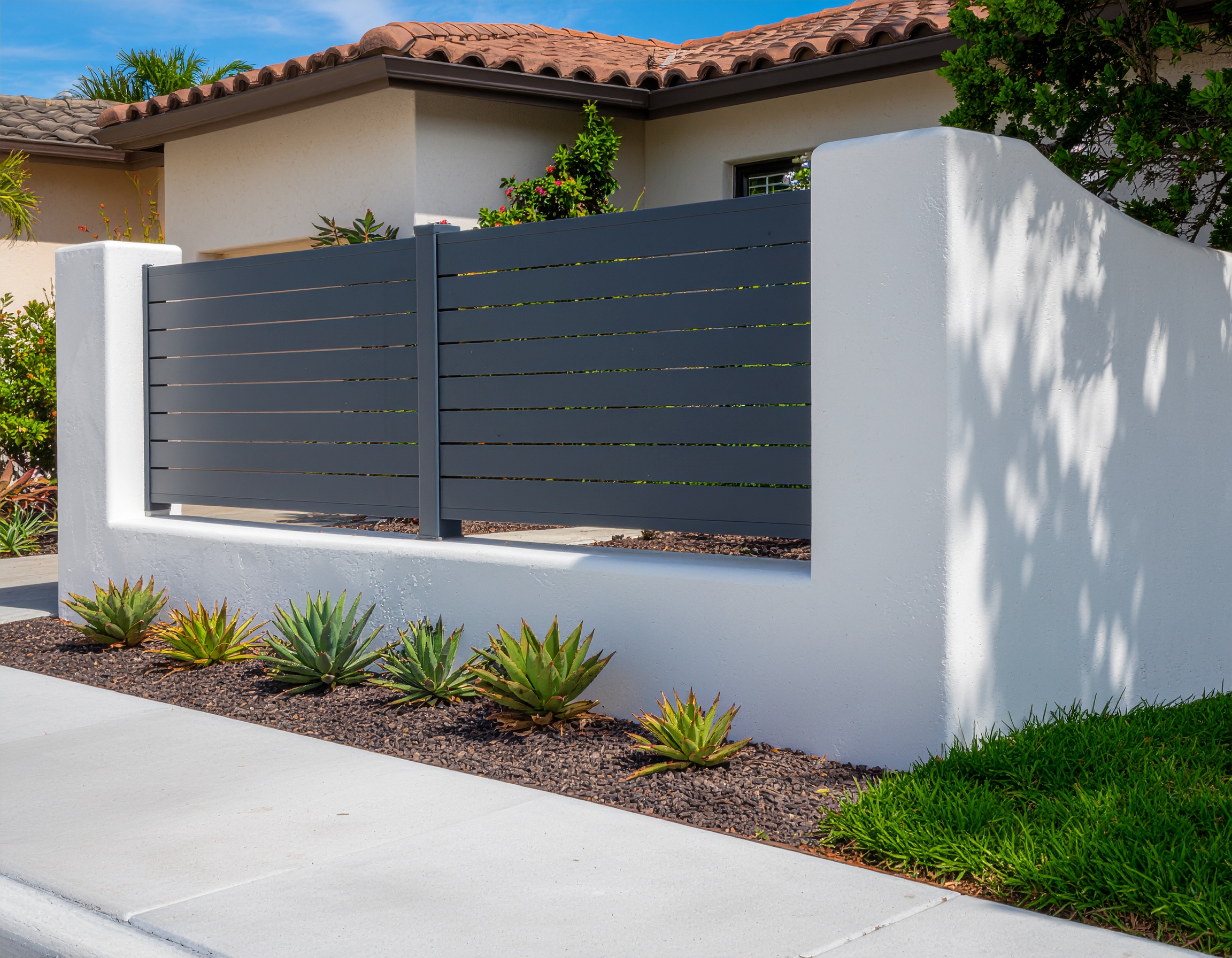 Modern black horizontal slat fence with a matching gate installed alongside a curv 192739 - San Antonio Deck and Fence Works Gray metal slat fence, white wall.-deck builder-San Antonio, Texas