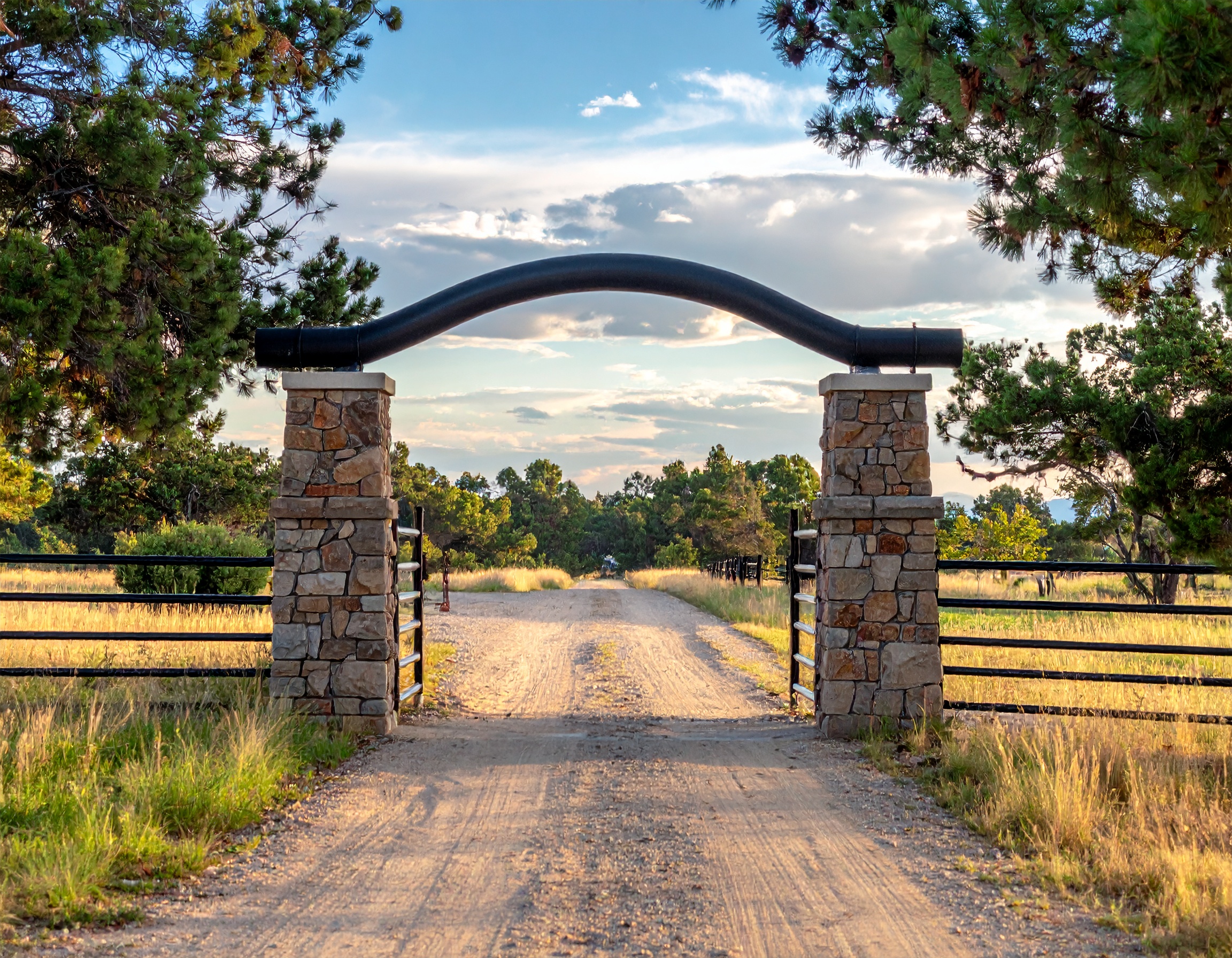Simple Ranch Entrance with Overhead Pipe Arch_Ranch entrance with two stone columns c 856922 - San Antonio Deck and Fence Works Stone pillars with black metal gate-deck builder-San Antonio, Texas